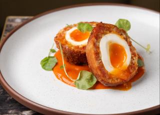 Scotch eggs sitting on a white plate
