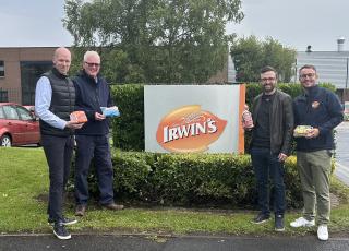 4 men stand outside a sign that said Irwin's Bakery holding a variety of baked goods